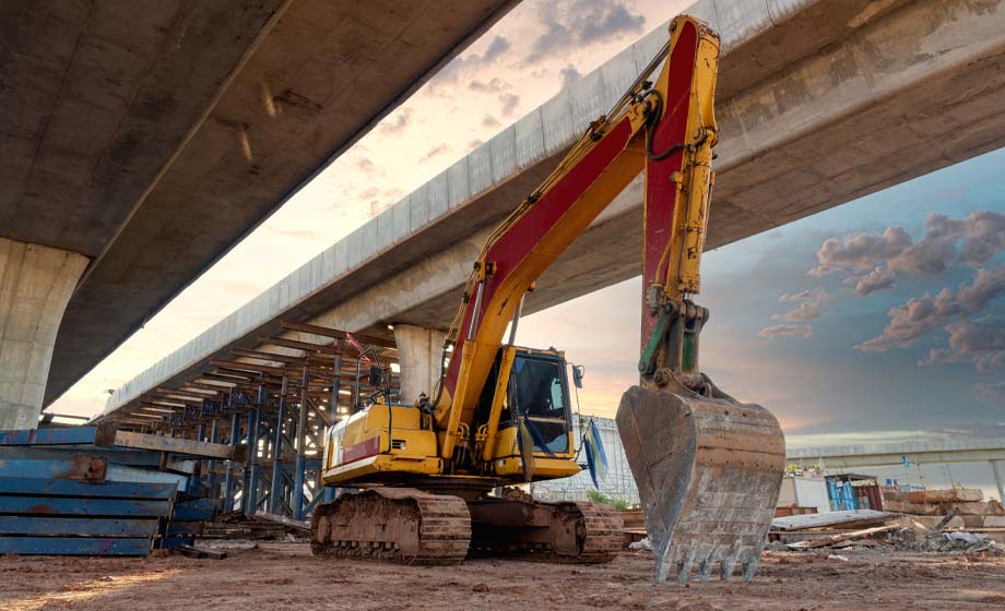 Image of an excavator beneath a highway bridge